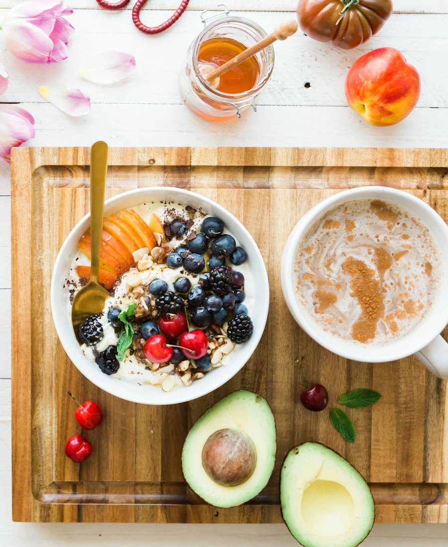 Desayuno con fruta, yogur y avena sobre una mesa con flores